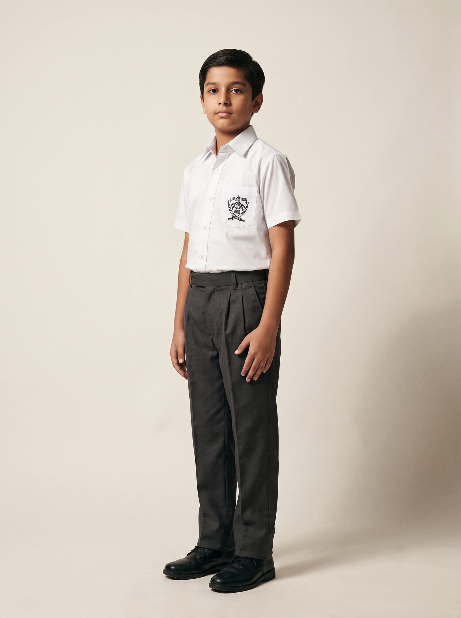 Flat-front trouser — White cotton-and-polyester shirting carrying the school crest, over charcoal grey trousers.